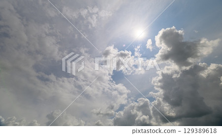 A picturesque dynamic sky adorned with fluffy clouds and radiant sunlight peeking through 129389618