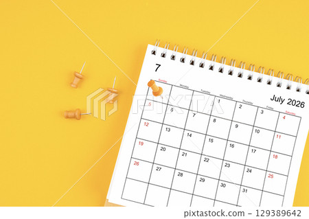 July 2026 Monthly desk calendar for 2026 year with wooden pin on yellow background. 129389642
