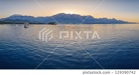 Seascape sunset panorama over the Mediterranean Sea near Kemer, Turkey. Panoramic view to the moonlight beach at dusk and the majestic Taurus mountains in the background Seascape sunset panorama over the Mediterranean Sea near Kemer, Turkey. Panoramic view to the moonlight beach at dusk and the majestic Taurus mountains in the background 129390742