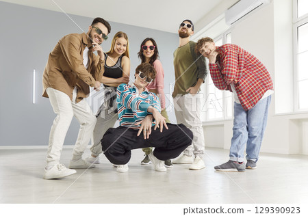 Cool hip hop dancer man, group of dancing people actively dancing indoors, moving posing in studio 129390923