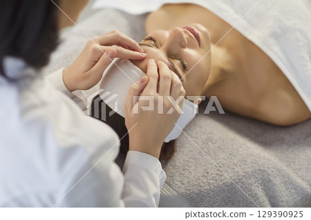 Close up photo of pretty young woman lying with closed eyes and having face or head massage in spa Close up photo of pretty young woman lying with closed eyes and having face or head massage in spa 129390925