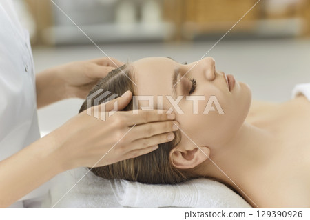 Beautiful dark haired woman has facial massage, feeling relaxed, keeping eyes closed Beautiful dark haired woman has facial massage, feeling relaxed, keeping eyes closed 129390926