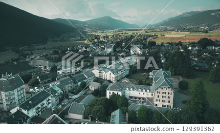 Drone aerial view of Villard-de-Lans in the Vercors region, showing residential areas, surrounding fields, and alpine mountains in summer Drone aerial view of Villard-de-Lans in the Vercors region, showing residential areas, surrounding fields, and alpine mountains in summer 129391362