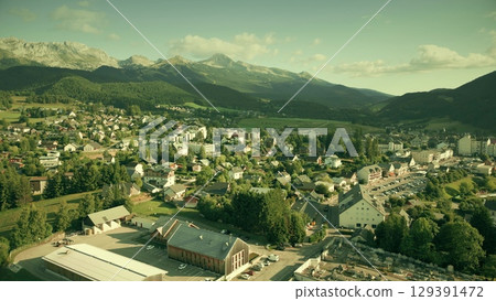 Aerial drone view of Villard-de-Lans in the French Alps with residential buildings, streets, and surrounding mountains under summer sunlight 129391472