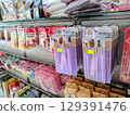 Close up of purple makeup brush sets neatly displayed on a store shelf alongside various cosmetic products.   129391476