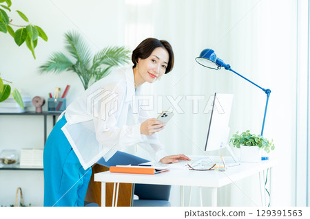 經營一部智能手機的女商人在辦公室 129391563