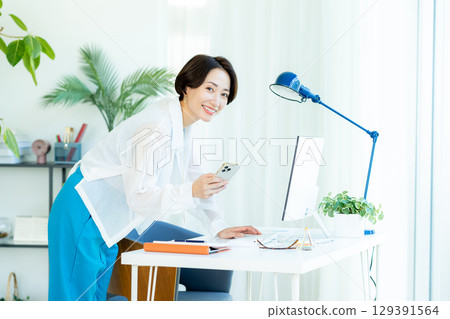 經營一部智能手機的女商人在辦公室 129391564