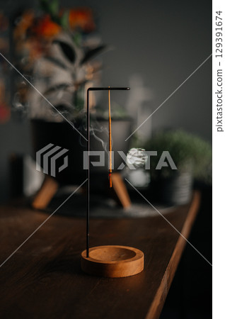 Incense stick smoldering in holder, burning candles, dry flowers and Tibetan singing bowl on wooden table outdoors Incense stick smoldering in holder, burning candles, dry flowers and Tibetan singing bowl on wooden table outdoors 129391674