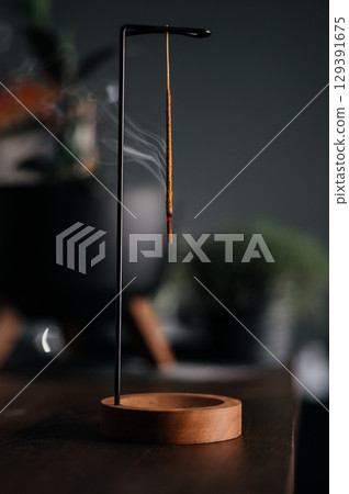 Incense stick smoldering in holder, burning candles, dry flowers and Tibetan singing bowl on wooden table outdoors Incense stick smoldering in holder, burning candles, dry flowers and Tibetan singing bowl on wooden table outdoors 129391675