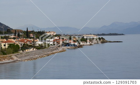 Serene Mediterranean village along coastline with picturesque views of sea and mountains in Greece reflecting tranquility of local life and natural beauty, capturing rural charm and simplicity Serene Mediterranean village along coastline with picturesque views of sea and mountains in Greece reflecting tranquility of local life and natural beauty, capturing rural charm and simplicity 129391703