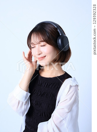 Image of a woman listening to music with headphones 129392328