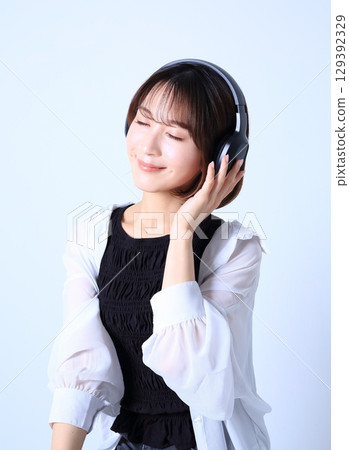 一位女士戴著耳機聽音樂的圖片 129392329