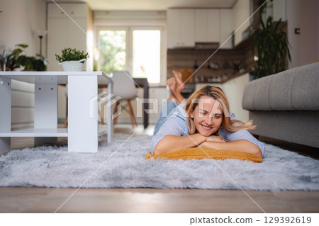 Woman relaxing on carpet in living room enjoying weekend Woman relaxing on carpet in living room enjoying weekend 129392619