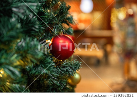 Close-up of golden and red Christmas ornaments on festive tree with holiday lights Close-up of golden and red Christmas ornaments on festive tree with holiday lights 129392821