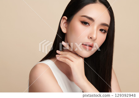 A beautiful young Asian woman with clean, fresh skin against a beige background. Skincare, facial treatment, cosmetology, beauty, and spa. An elegant portrait of an Asian woman. A beautiful young Asian woman with clean, fresh skin against a beige background. Skincare, facial treatment, cosmetology, beauty, and spa. An elegant portrait of an Asian woman. 129392948