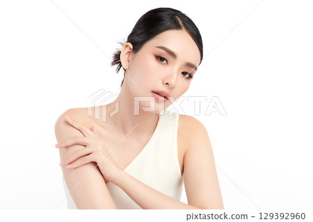 A beautiful young Asian woman with clean, fresh skin against a white background. Skincare, facial treatment, cosmetology, beauty, and spa. An elegant portrait of an Asian woman. 129392960