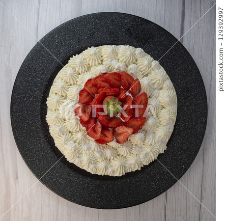 Delightful fraisier cake topped with fresh strawberries and whipped cream is served at a gathering Delightful fraisier cake topped with fresh strawberries and whipped cream is served at a gathering 129392997