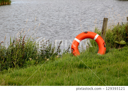 Red and White Life Preserver at a Rural Lakeside Location on a Summer Morning 129393121