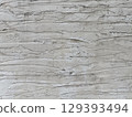 Close up of textured concrete wall with rough, layered surface showing natural cracks and crevices, creating aged, weathered appearance 129393494