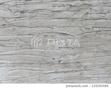 Close up of textured concrete wall with rough, layered surface showing natural cracks and crevices, creating aged, weathered appearance 129393494