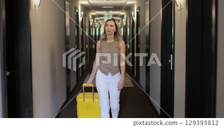 Woman with suitcase in the hallway at the hotel. Check in at the hotel. Showcasing a modern travel experience. Woman with suitcase in the hallway at the hotel. Check in at the hotel. Showcasing a modern travel experience. 129393812