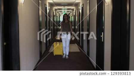 Woman with suitcase in the hallway at the hotel. Check in at the hotel. Showcasing a modern travel experience. 129393813