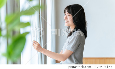 Woman opening curtain Woman opening curtain 129394167