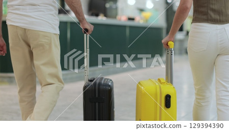 Close up. Tourists arriving with suitcase at hotel front desk. Two people with luggage checking in. Travel and reception desk concept. Close up. Tourists arriving with suitcase at hotel front desk. Two people with luggage checking in. Travel and reception desk concept. 129394390