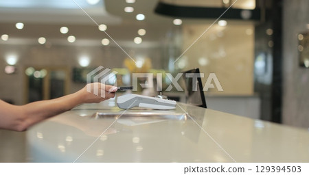 Customer with mobile phone pay for hotel reception, payment. Client, concierge service or people at help desk. Person at reception desk and doing check. Close up. 129394503