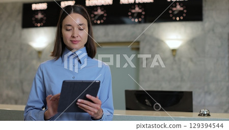 Portrait of receptionist woman with tablet in lobby for booking schedule, check in app or reservation. Concierge service, woman smile in lobby for check in assistance, reservation and help. Portrait of receptionist woman with tablet in lobby for booking schedule, check in app or reservation. Concierge service, woman smile in lobby for check in assistance, reservation and help. 129394544