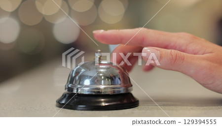 Close-up of woman hands ringing call bell in hotel. Client is waiting for administrator in lobby. Close-up of woman hands ringing call bell in hotel. Client is waiting for administrator in lobby. 129394555