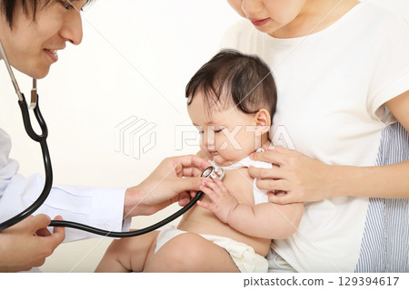 A baby being examined with a stethoscope while being held by his mother A baby being examined with a stethoscope while being held by his mother 129394617