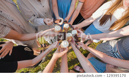 Group of school friends enjoying ice cream cones and chocolate bars together in a sunny day 129395170