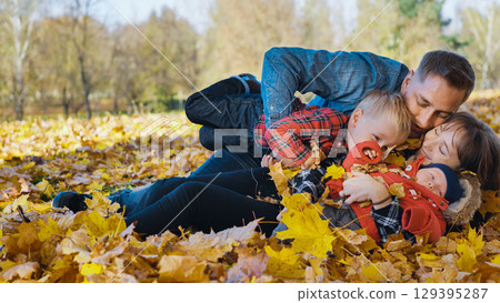 Family playing and laughing among fallen autumn leaves, sharing warm moments in golden sunlight of scenic park landscape Family playing and laughing among fallen autumn leaves, sharing warm moments in golden sunlight of scenic park landscape 129395287