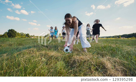 Teenagers having fun playing soccer in a field during their summer break 129395298