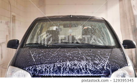 A worker coats a car with wax after washing the car. A worker coats a car with wax after washing the car. 129395345