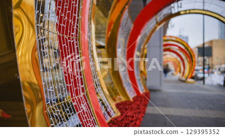 Christmas decorations creating a tunnel of lights in a city street 129395352