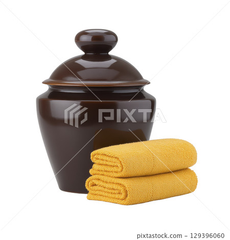Glossy brown ceramic jar with lid is paired with two neatly folded yellow towels, creating harmonious and cozy arrangement 129396060
