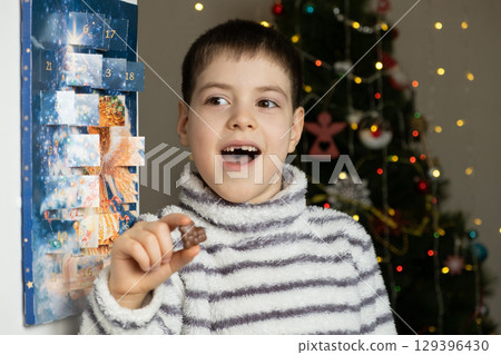 A happy child took out chocolate from the advent calendar. Preparing for Christmas A happy child took out chocolate from the advent calendar. Preparing for Christmas 129396430