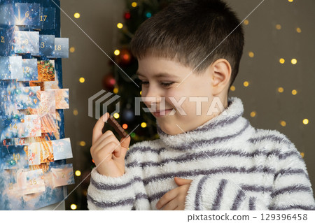 A little boy holding a chocolate Santa figurine from the advent calendar in his hands 129396458