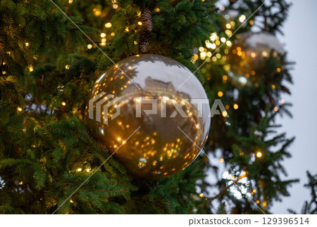Close-up of Christmas tree branches with golden balls and festive lights 129396514