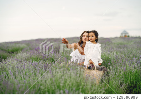 Mother with little daughter on lavender background. Beautiful woman and cute baby playing in meadow field. Family holiday in summer day. Mother with little daughter on lavender background. Beautiful woman and cute baby playing in meadow field. Family holiday in summer day. 129396999