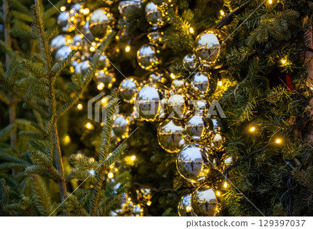 Close-up of Christmas tree decorated with shiny golden baubles and festive lights Close-up of Christmas tree decorated with shiny golden baubles and festive lights 129397037