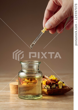 Dropping essential oil or herbal tincture into a glass bottle. 129397078