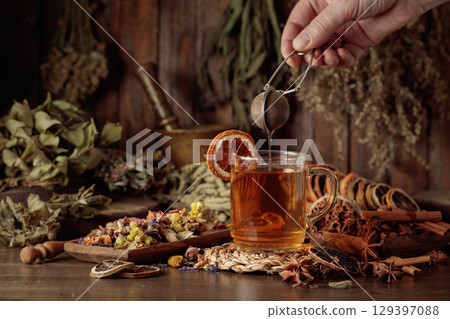 Cup of herbal tea with various dried herbs, flowers, and spices. 129397088