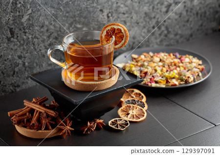 Cup of herbal tea with ingredients and slices of dried orange slices. 129397091