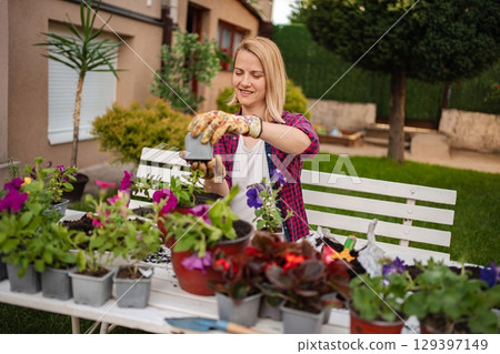 Gardener enjoys potting colorful flowers in sunny yard Gardener enjoys potting colorful flowers in sunny yard 129397149