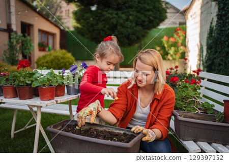 Mother and daughter gardening together in their backyard 129397152