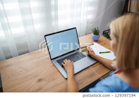 Female doctor making online payment using laptop and credit card Female doctor making online payment using laptop and credit card 129397194