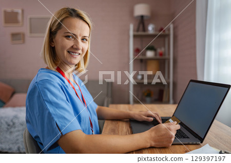 Female doctor is making an online purchase using her credit card and laptop 129397197